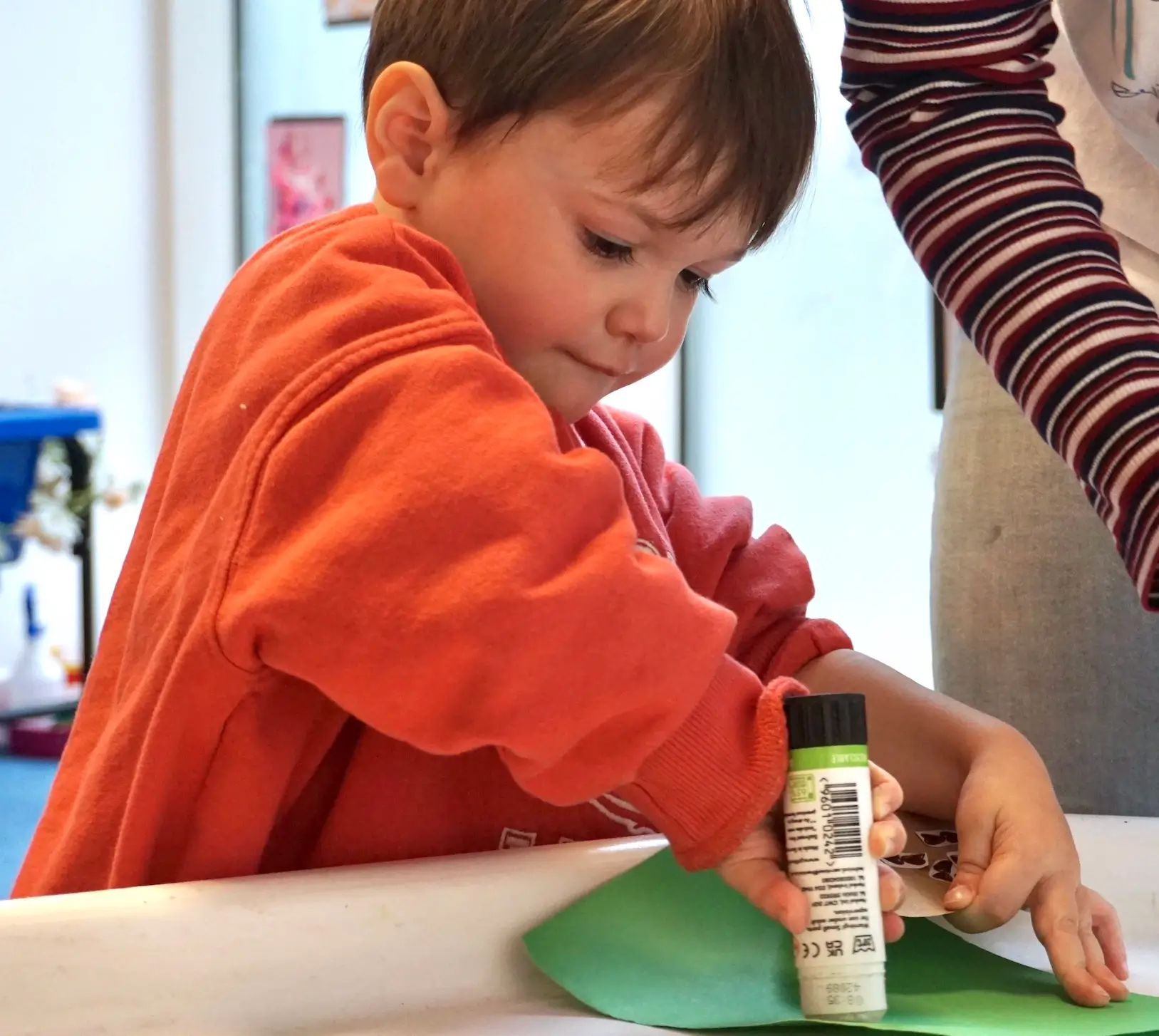 Autistic child doing arts and craft, holding a glue stick and applying it on a piece of paper
