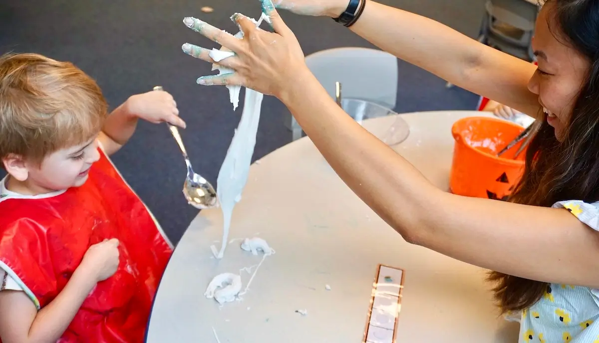 A little autistic boy playing with his therapist with cornflour slime