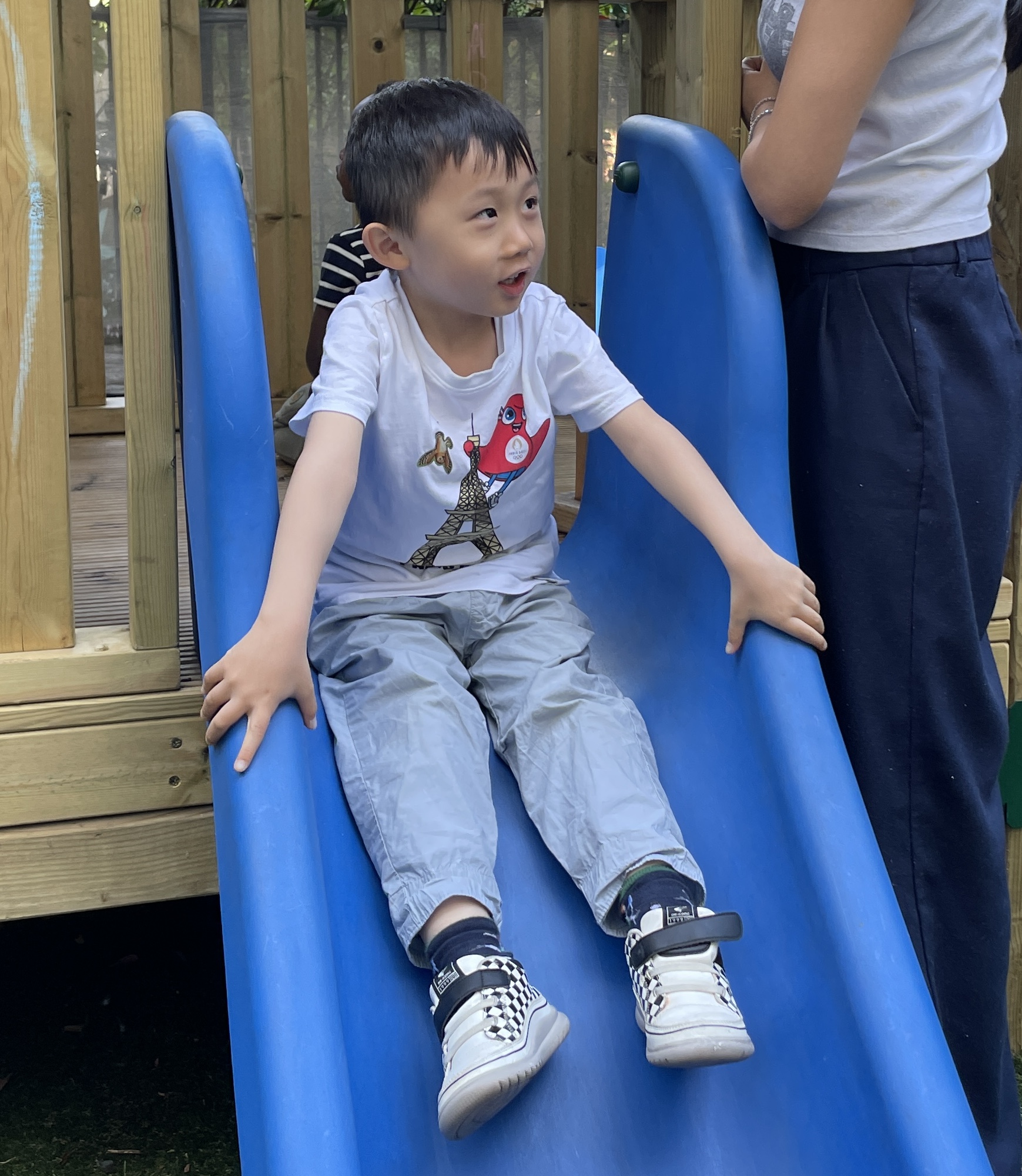 Picture of an autistic little boy smiling and waving at the camera